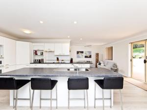 a kitchen with a large island with bar stools at Fingal Escape 28 Bent St in Fingal Bay