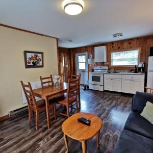 a living room filled with furniture and a table at Knotty Pine Cottages, Suites & Motel Rooms in Ingonish Beach