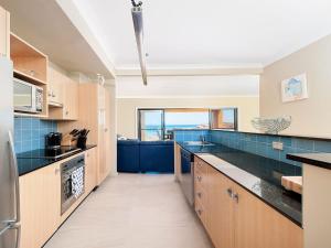a kitchen with blue tile and a large window at Birubi Point Anna Bay 17A in Anna Bay