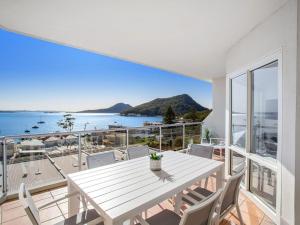 una mesa blanca en el balcón con vistas al océano en Breakwater Apartment 403, en Shoal Bay