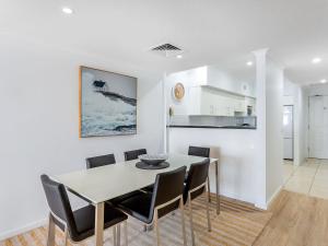 cocina y comedor con mesa y sillas en Breakwater Apartment 403, en Shoal Bay