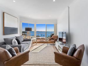 a living room with couches and a view of the ocean at Breakwater Apartment 403 in Shoal Bay