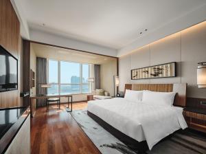 sypialnia z dużym łóżkiem i dużym oknem w obiekcie HUALUXE Ningbo Harbor City, an IHG Hotel w mieście Ningbo
