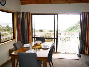 a dining room with a table and chairs and a large window at Bush Henge - Tata Beach Holiday Home in Tarakohe
