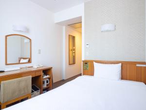a bedroom with a bed and a desk and a mirror at Hotel Belleview Nagasaki Dejima in Nagasaki