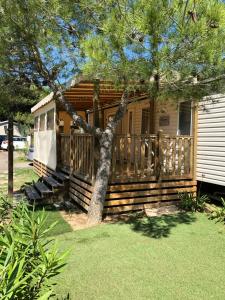 ein Holzhaus mit einer Veranda und einem Baum in der Unterkunft Mobilhome 2 Chambres 2 SDB in Canet-en-Roussillon