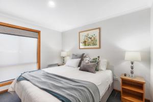 a white bedroom with a bed and a window at City Four Apartment in Mount Gambier