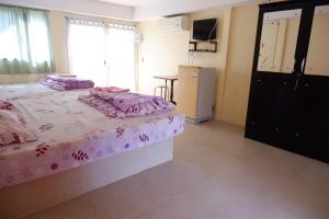Un dormitorio con una cama, una mesa y un frigorífico. en Baan Rai Pray Rung Kaeng Krachan, en Ban Tha Ling Lom