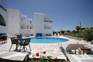 a pool with chairs and a table in front of a building at Sunny Beach Studios in Naxos Chora