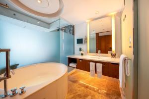a bathroom with a tub and a large mirror at The Eton Hotel Shanghai in Shanghai