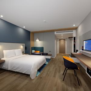 een slaapkamer met een groot wit bed en een bureau bij Holiday Inn Express Chongqing Airport Zone, an IHG Hotel in Chongqing