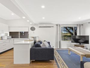 a living room with a couch and a kitchen at Blue Fish 41 Boulder Bay Road in Fingal Bay