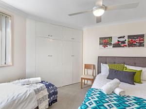 a bedroom with two beds and a ceiling fan at Karinya at Little Beach Upstairs in Nelson Bay