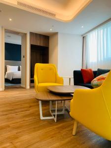 Zimmer mit gelben Stühlen, einem Tisch und einem Bett in der Unterkunft Holiday Inn Express Chongqing Airport Zone, an IHG Hotel in Chongqing