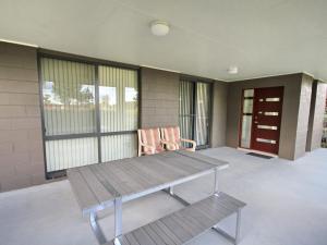 einen Tisch und einen Stuhl auf einer Veranda mit Fenstern in der Unterkunft Frasers Cottage in Laurieton + 3 Fotos