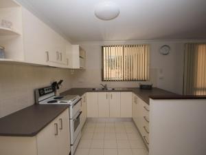 a kitchen with white cabinets and black counter tops at Frasers Cottage 23 Castle St Laurieton in Laurieton