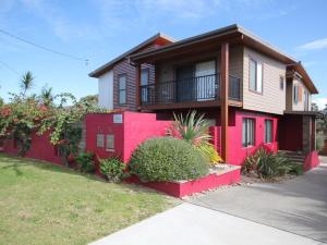 a red house with a balcony on a street at Rio Grande 11B Bergalia Cres Dunbogan in North Haven