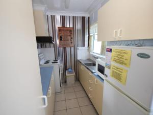 a kitchen with a white refrigerator and a sink at Beachfront 3 Unit 3 of 12 Bundella Ave LC in Lake Cathie