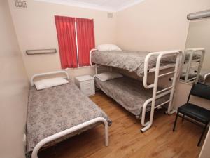 a small room with two bunk beds and a chair at Beachfront 3 Unit 3 of 12 Bundella Ave LC in Lake Cathie