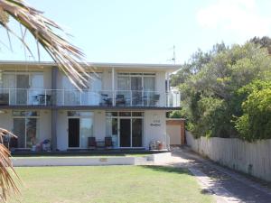 a white house with a fence and a yard at Beachfront 3 Unit 3 of 12 Bundella Ave LC in Lake Cathie