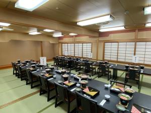 a large room with black tables and chairs at Kibi Kogen Resort Hotel in Kaga