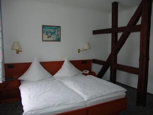 a bedroom with a bed with white sheets and a ladder at Hotel Landhaus Greene in Einbeck