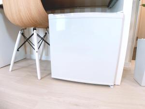 a white refrigerator in a kitchen next to a stool at Bar & Hotel Colors MIYAJIMA in Hatsukaichi
