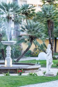 a fountain with a statue in a park with palm trees at The Rif - Boutique Hotel in Pisa