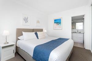 a white bedroom with a bed and a bathroom at Suite 310 Sandcastles 3 Bedroom Deluxe in Perth