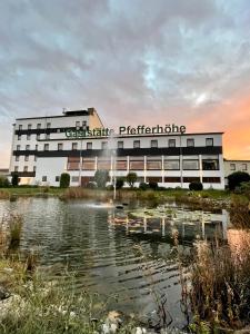 ein Gebäude mit einem Teich davor in der Unterkunft Pfefferhöhe Hotel & Restaurant in Alsfeld