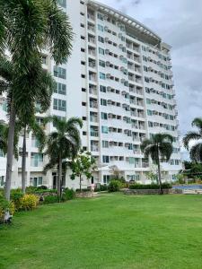 a large building with palm trees in front of a park at Anuva Condominium with Netflix in Manila