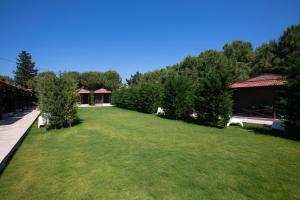 einen großen grünen Hof mit Bäumen und Gebäuden in der Unterkunft AEGEAN Apartments - Bungalows in Alacati