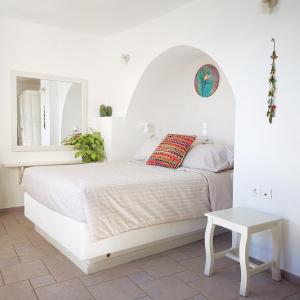 a white bedroom with a bed and a table at Spitia Tzitzi in Imerovigli