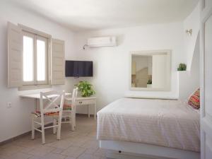 a bedroom with a bed and a desk and a mirror at Spitia Tzitzi in Imerovigli
