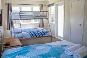 a bedroom with two bunk beds and a window at Rehutai Beach House in Paihia