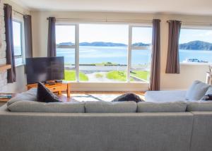 a living room with a couch and a large window at Rehutai Beach House in Paihia