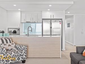 a kitchen with white cabinets and a stainless steel refrigerator at The Shoal 401 in Shoal Bay