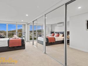 two beds in a bedroom with glass walls at The Shoal 401 in Shoal Bay