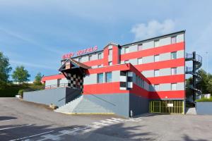 ein rotes und weißes Gebäude mit Treppen auf einem Parkplatz in der Unterkunft Enzo Hotels Nancy Frouard by Kyriad Direct in Frouard