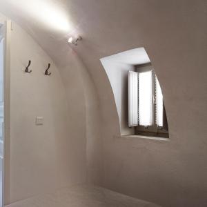 a white room with a mirror and a window at Spitia Tzitzi in Imerovigli