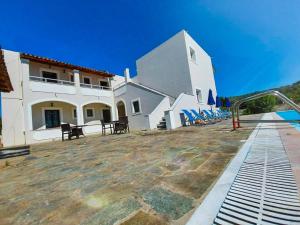 a white building with chairs in front of it at Vista Verde Apartments in Sidari