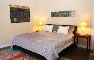 a bedroom with a bed with two lamps and a painting at Deer Run- Creekhouse in Wimberley