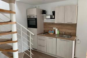 a small kitchen with white cabinets and a staircase at Ferienhaus im Igelbau in Baabe