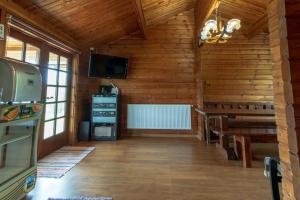 Habitación con paredes de madera y comedor con TV. en Cabana Dopca, en Racoşu de Jos