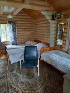 a bedroom with two beds and a blue chair at Ellu in Kangasniemi