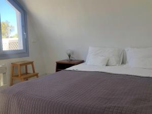 a bedroom with a bed with a purple blanket and a window at Thera Incognita Studios in Perissa