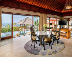 a dining room with a table and chairs and a balcony at The Edge Bali in Uluwatu