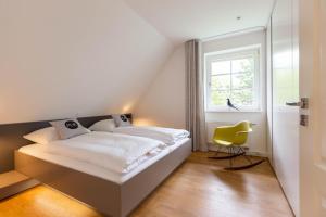 a bedroom with a bed and a yellow chair at Pur A4 in Wustrow