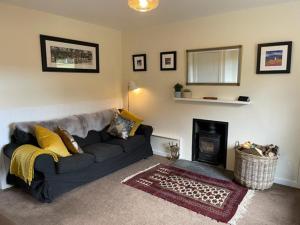 a living room with a couch and a fireplace at Jock's Cottage on the Blarich Estate in Rogart