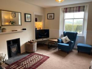 uma sala de estar com lareira e 2 cadeiras e uma televisão em Jock's Cottage on the Blarich Estate em Rogart